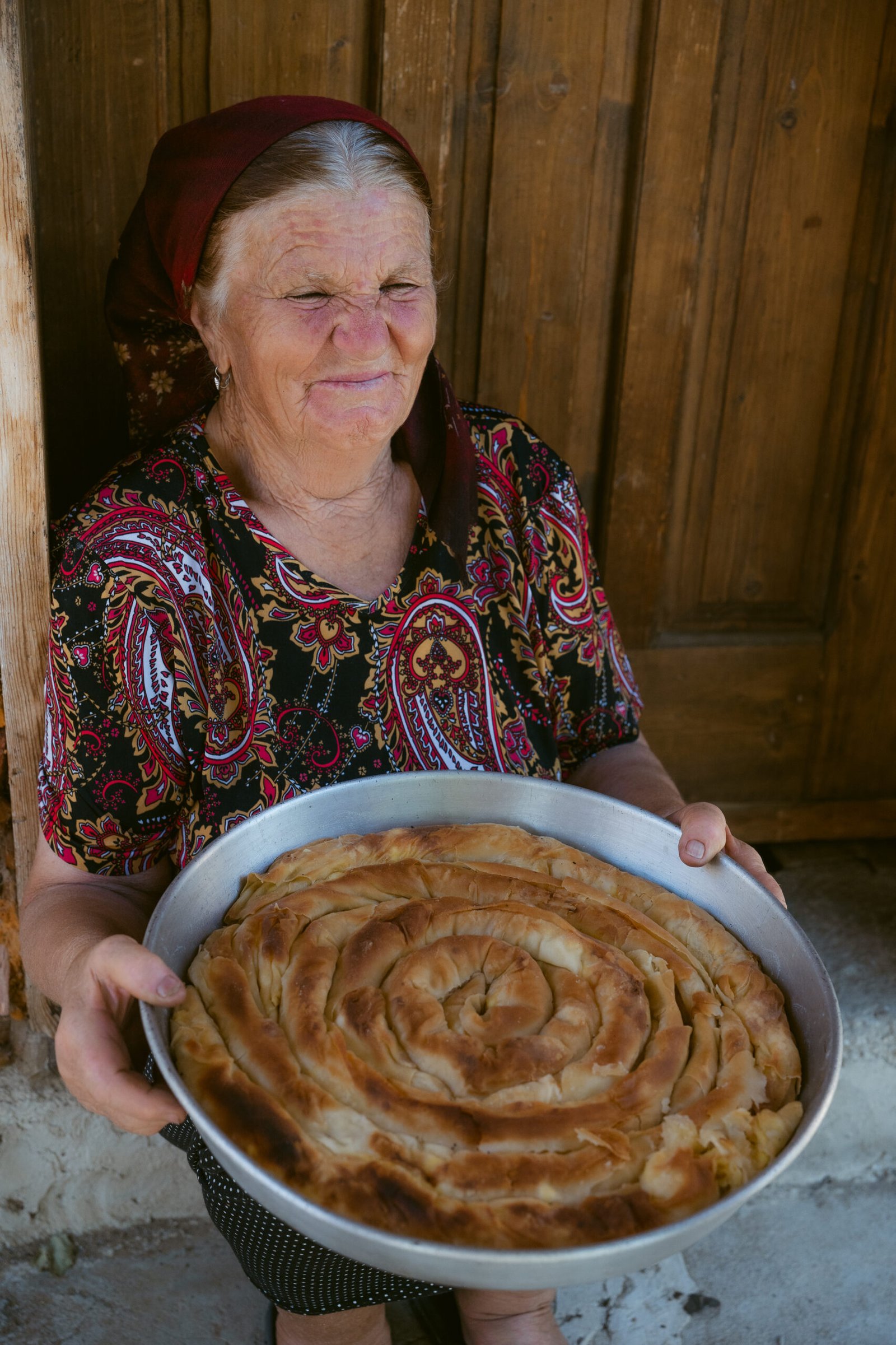 Баба държи тава с изпечена баница